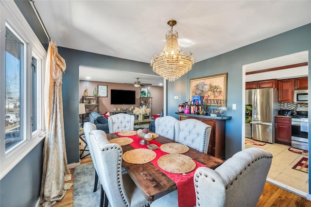 dining room featuring light wood-style floors and ceiling fan with notable chandelier