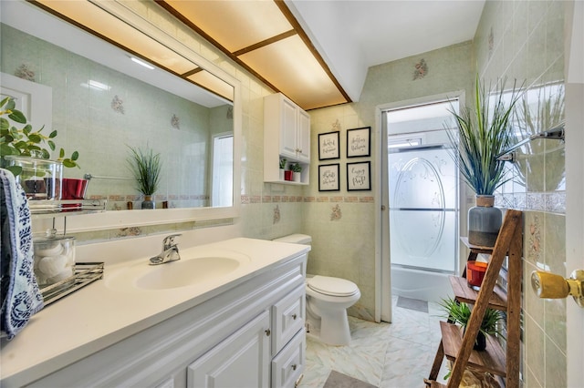 full bath featuring toilet, marble finish floor, vanity, and tile walls