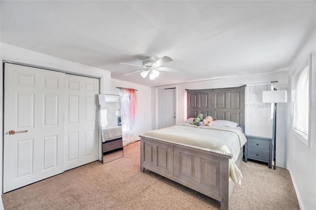 bedroom with light carpet, ceiling fan, and two closets