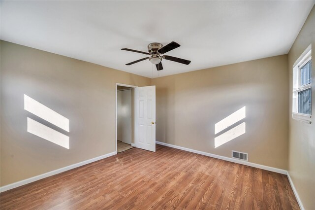 spare room with visible vents, ceiling fan, baseboards, and wood finished floors