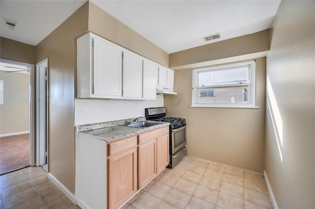 kitchen featuring light countertops, visible vents, stainless steel range with gas stovetop, a sink, and under cabinet range hood