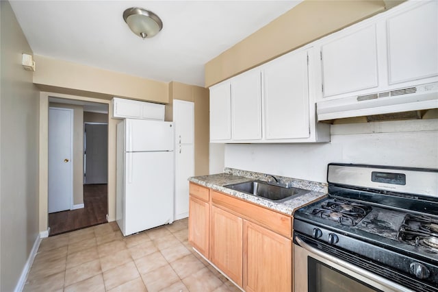 kitchen with stainless steel gas range oven, freestanding refrigerator, light countertops, under cabinet range hood, and a sink