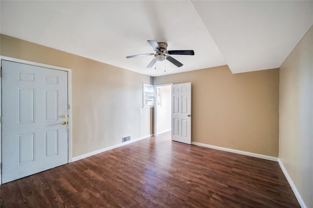 spare room with dark wood-style floors, visible vents, ceiling fan, and baseboards