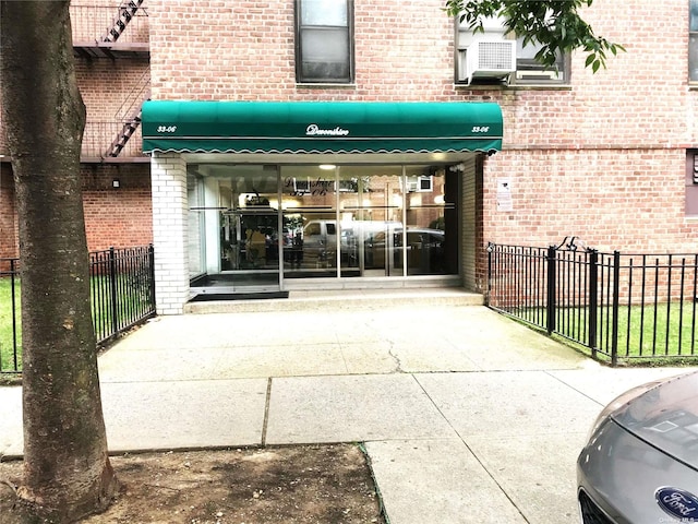 entrance to property featuring brick siding and fence