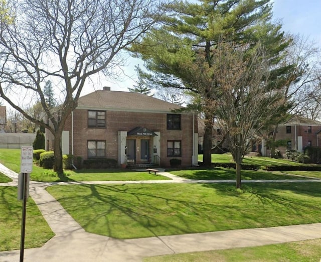 view of front of house with a front yard, fence, brick siding, and a chimney