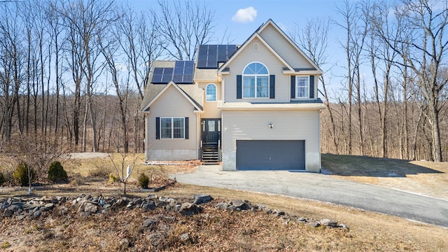 view of front facade featuring solar panels, aphalt driveway, and a garage