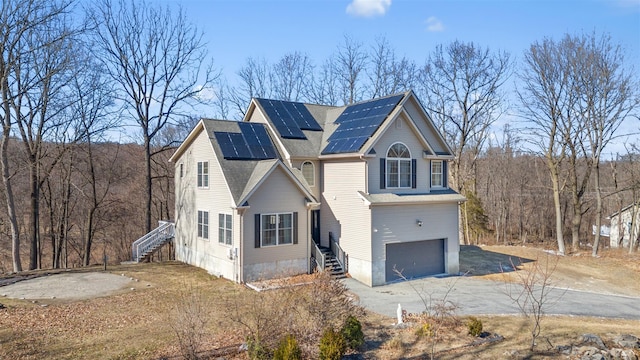 view of home's exterior with driveway, roof with shingles, solar panels, stairs, and a garage