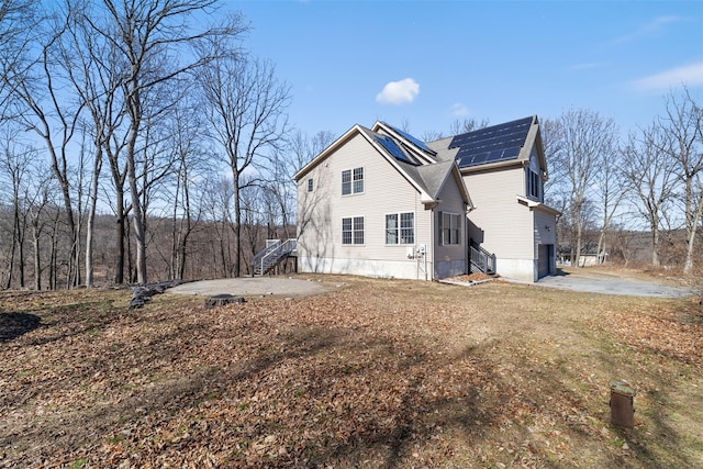 view of side of property with solar panels, stairway, and a shingled roof