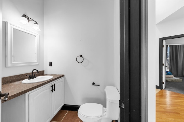 half bathroom featuring vanity, toilet, baseboards, and tile patterned flooring