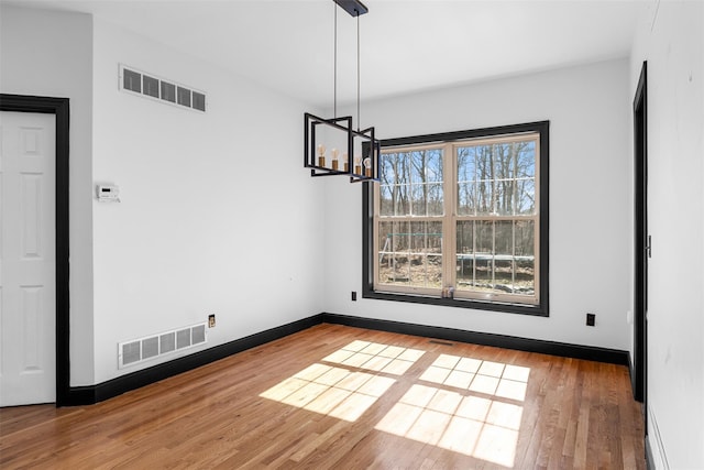 unfurnished dining area featuring visible vents, baseboards, and wood finished floors