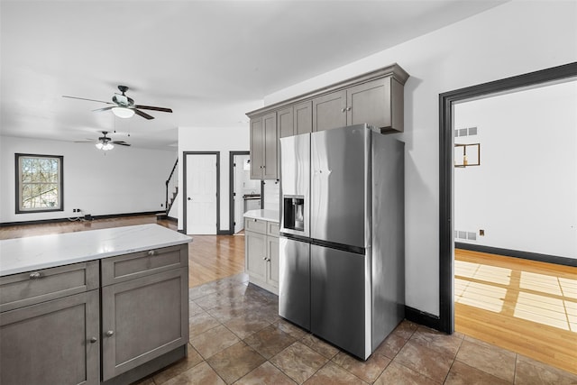 kitchen featuring visible vents, gray cabinetry, light stone countertops, stainless steel fridge with ice dispenser, and dark wood-style floors