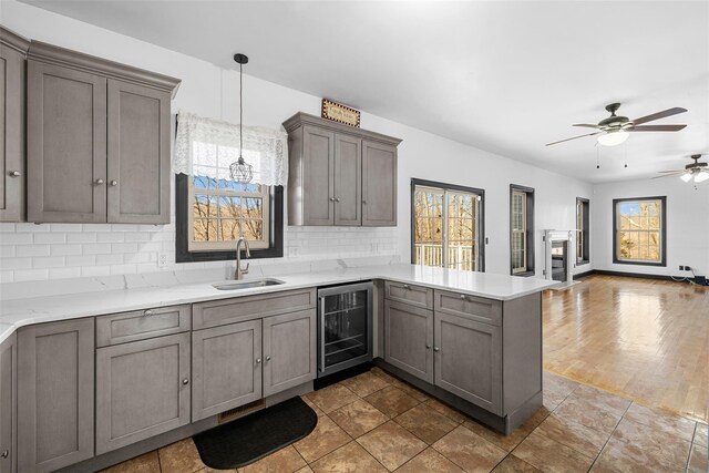 kitchen featuring wine cooler, a healthy amount of sunlight, a peninsula, and a sink