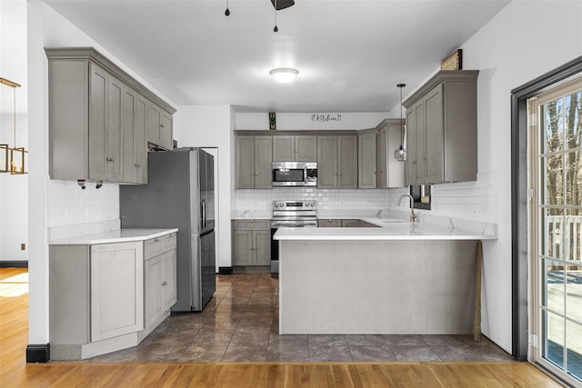 kitchen featuring gray cabinets, a peninsula, stainless steel appliances, and a sink