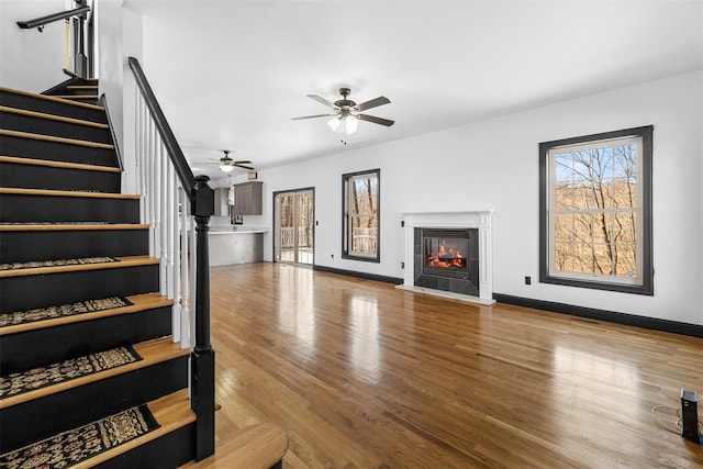 living area featuring stairway, baseboards, wood finished floors, and a tiled fireplace