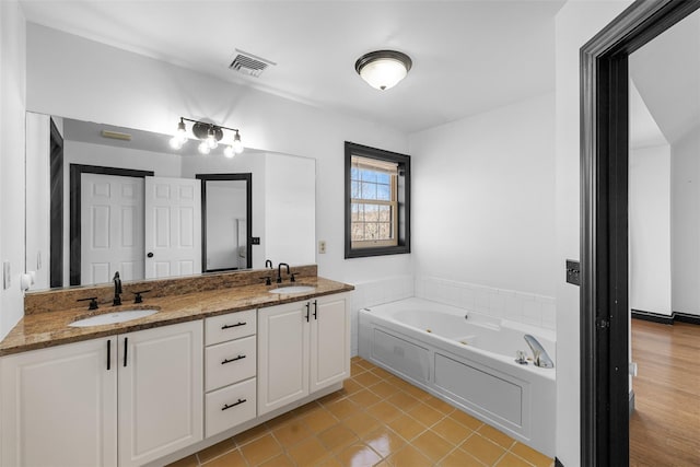 full bathroom featuring a sink, visible vents, a garden tub, and double vanity