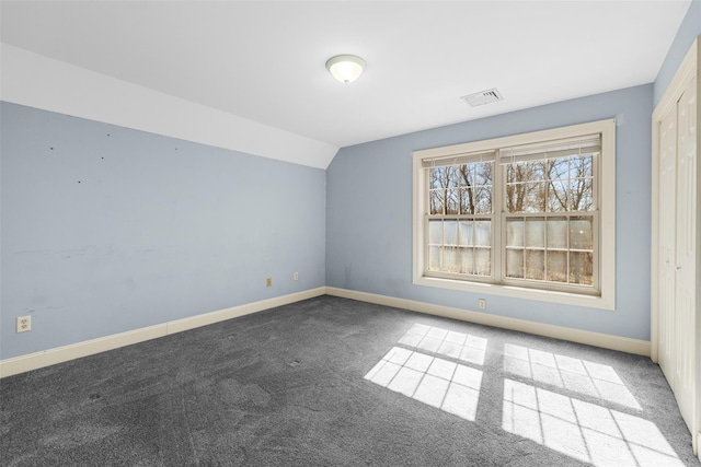 unfurnished room with baseboards, lofted ceiling, carpet floors, and visible vents