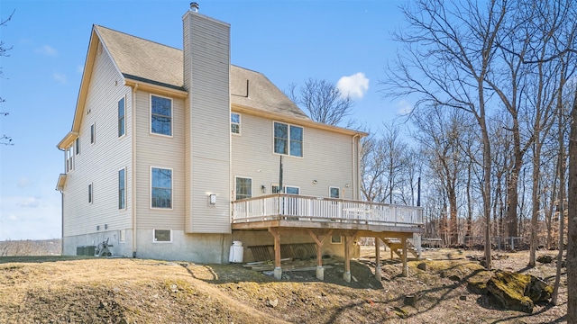 back of property featuring a shingled roof, a wooden deck, central air condition unit, and a chimney