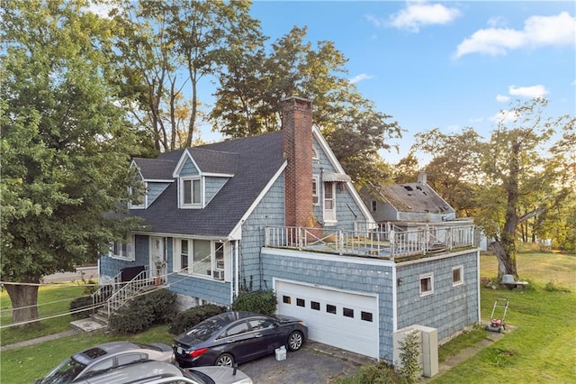 shingle-style home with a garage, a shingled roof, driveway, a front lawn, and a chimney