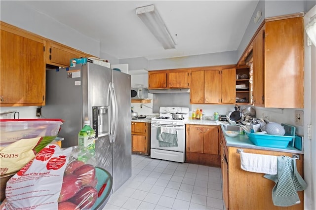 kitchen with white appliances, light tile patterned floors, brown cabinets, under cabinet range hood, and open shelves