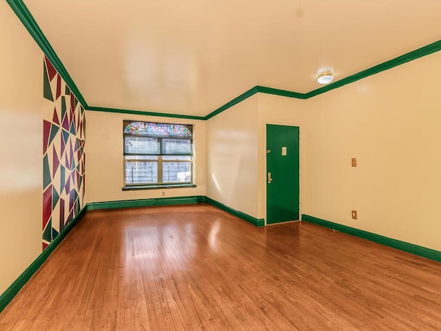 empty room featuring ornamental molding, baseboard heating, baseboards, and hardwood / wood-style floors