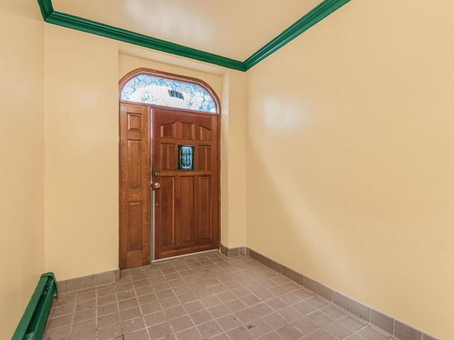 foyer entrance featuring baseboards, light tile patterned floors, baseboard heating, and crown molding