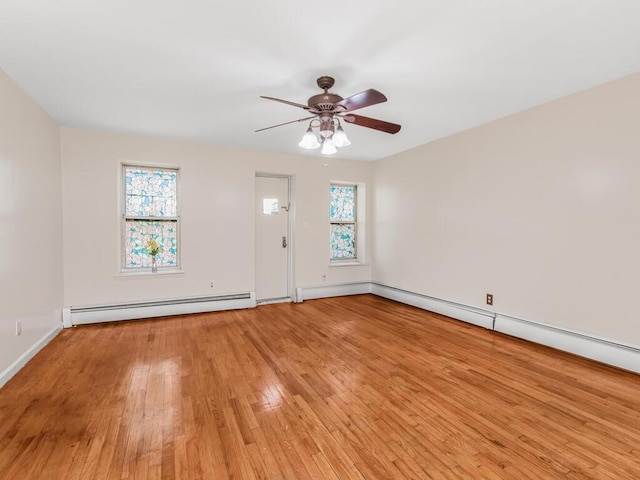 interior space featuring a baseboard heating unit, a healthy amount of sunlight, light wood finished floors, and a ceiling fan