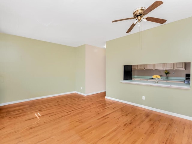 unfurnished living room with ceiling fan, light wood-style floors, and baseboards