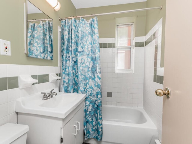 bathroom featuring toilet, shower / bathtub combination with curtain, tile walls, and vanity