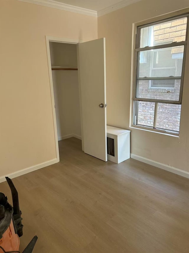 unfurnished bedroom featuring multiple windows, crown molding, baseboards, and wood finished floors