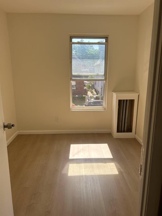 spare room featuring baseboards and wood finished floors