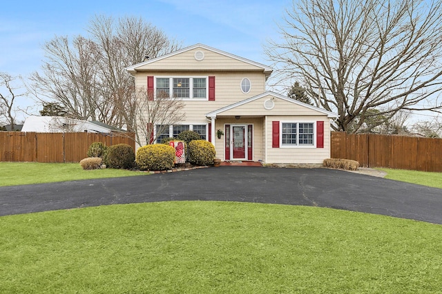 traditional home with fence, aphalt driveway, and a front yard