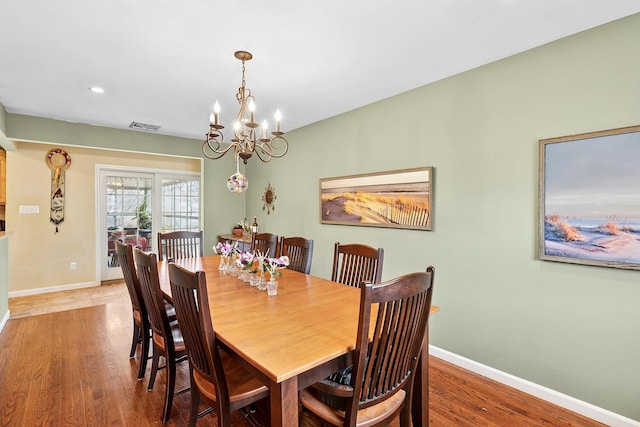 dining area with baseboards, visible vents, a chandelier, and wood finished floors