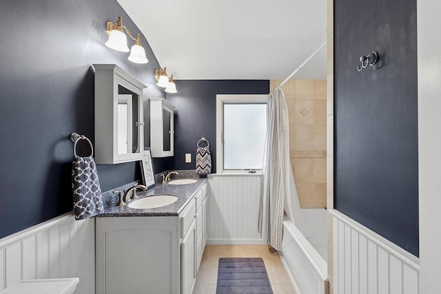 bathroom with double vanity, shower / bath combo with shower curtain, a sink, and wainscoting