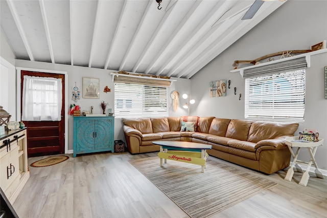 living room with lofted ceiling with beams, light wood-type flooring, a wealth of natural light, and baseboards