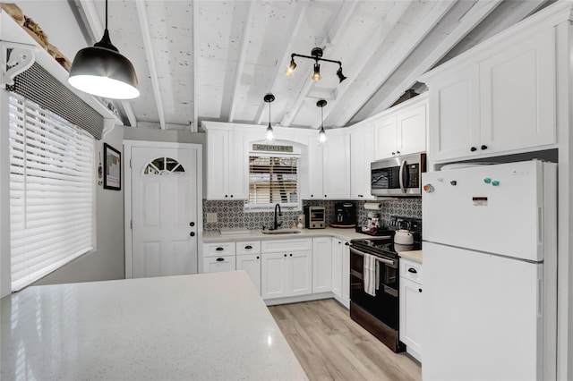 kitchen with light countertops, stainless steel microwave, freestanding refrigerator, a sink, and black range with electric cooktop