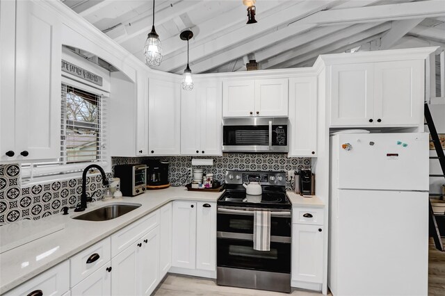 kitchen with lofted ceiling with beams, appliances with stainless steel finishes, light countertops, and a sink