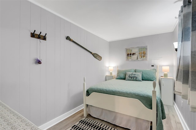 bedroom featuring light wood-style floors, crown molding, and baseboards