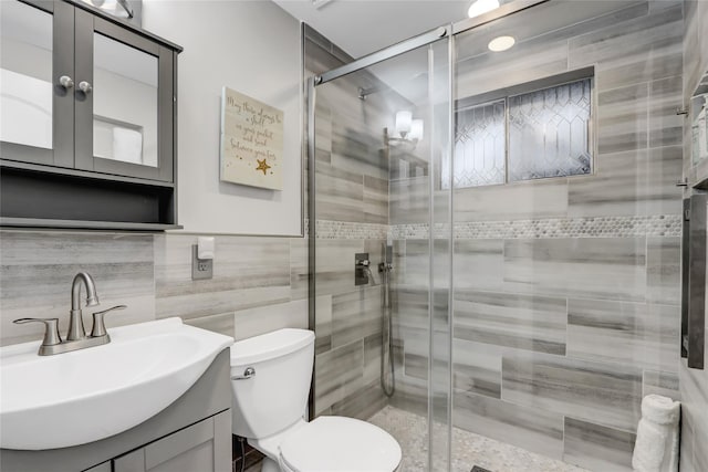 bathroom featuring toilet, a shower stall, and vanity