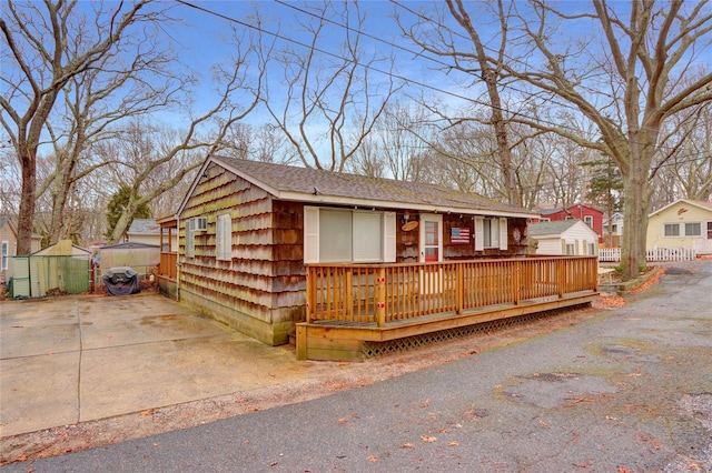 ranch-style home featuring roof with shingles and a wooden deck