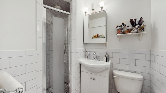 bathroom featuring toilet, a stall shower, tile walls, and vanity