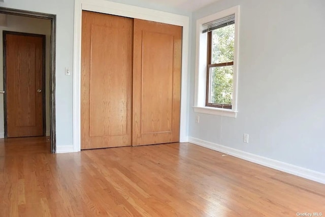 unfurnished bedroom featuring baseboards, a closet, and light wood-style floors