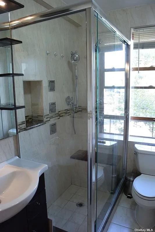 bathroom with vanity, a shower stall, toilet, and tile patterned floors