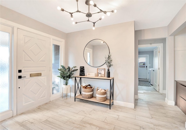 foyer entrance with light wood-style floors, plenty of natural light, separate washer and dryer, and an inviting chandelier