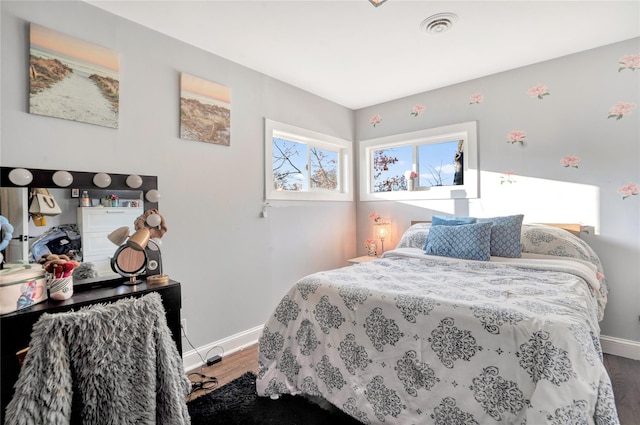 bedroom with visible vents, baseboards, and wood finished floors