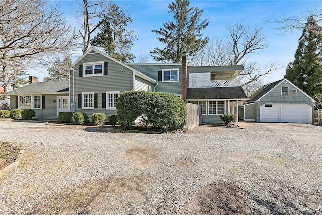 view of front of property featuring a detached garage, a chimney, and an outdoor structure