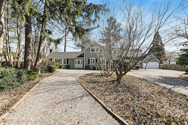 view of front of house featuring an outbuilding, driveway, and fence