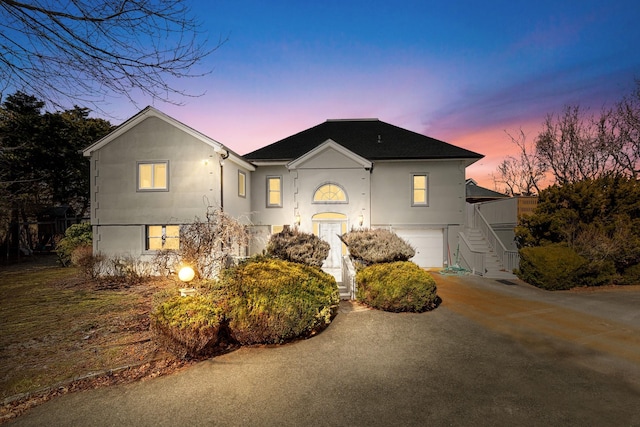 view of front facade with an attached garage, stairs, concrete driveway, and stucco siding