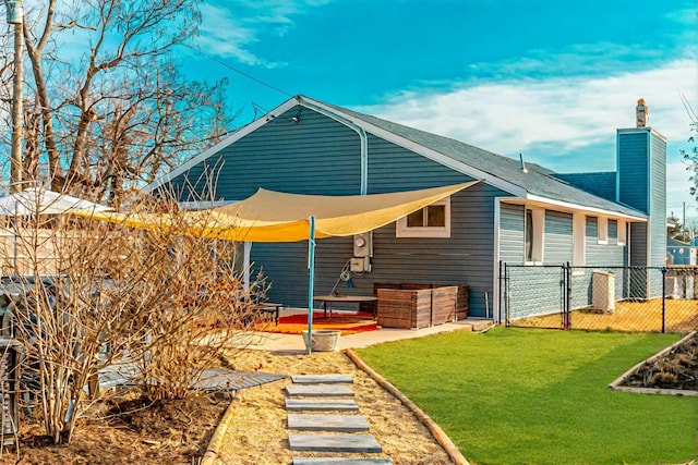 rear view of property with fence, a lawn, a gate, a chimney, and a patio area