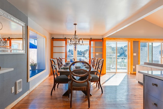 dining space featuring baseboards, wood finished floors, visible vents, and an inviting chandelier