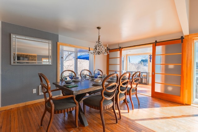 dining space with wood-type flooring, baseboards, a wealth of natural light, and a barn door